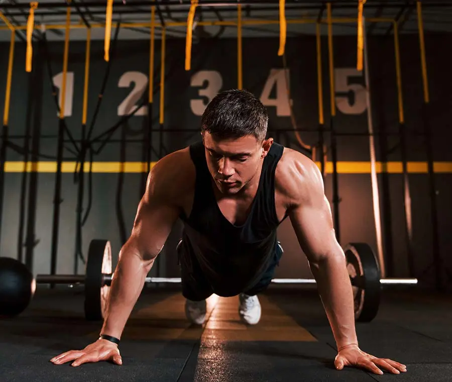 Strong man in sportive clothes doing push-ups in the gym