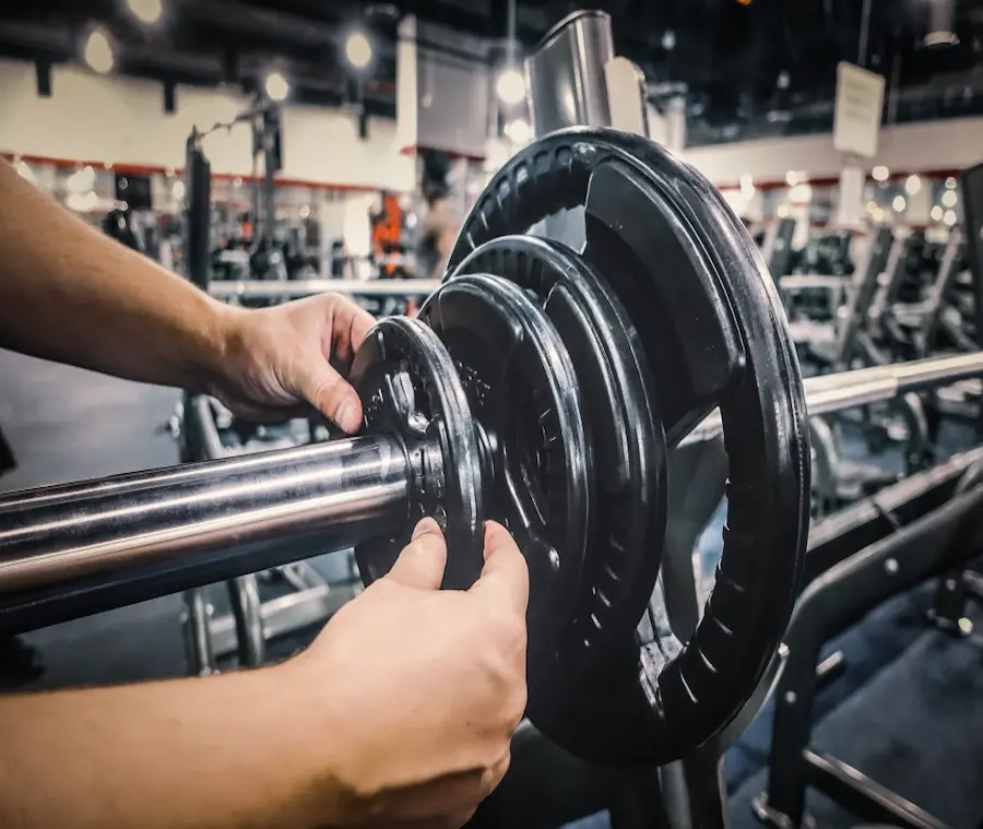 man-loading-weights-on-bench-press-exercise-station-at-the-gym_t20_pY1LNe